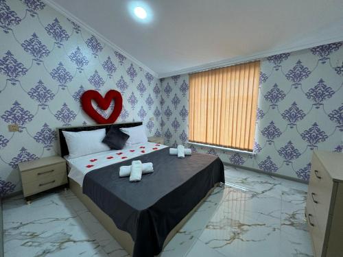 a bedroom with a bed with a heart on the wall at Qebele Kiraye Gunluk in Gabala