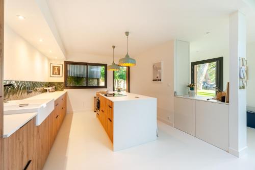 cocina grande con encimeras blancas y ventana grande en La Cabane des Vagues à Préfailles, en Préfailles