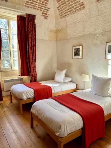 Cette chambre comprend 2 lits avec des draps rouges et blancs. dans l'établissement Les Chambres de l'Abbaye, à Saintes