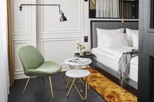a bedroom with a bed and a chair and a table at Roomers Munich, Autograph Collection in Munich