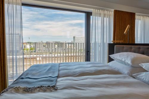 a bedroom with a large window with a view of a city at Roomers Munich, Autograph Collection in Munich