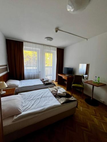 a hotel room with two beds and a desk at Geovita Lądek Zdrój in Lądek-Zdrój