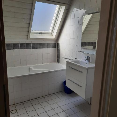 a bathroom with a sink and a bath tub and a window at De Gouwe, 158 - aan visvijver, de beste visstek in Gramsbergen