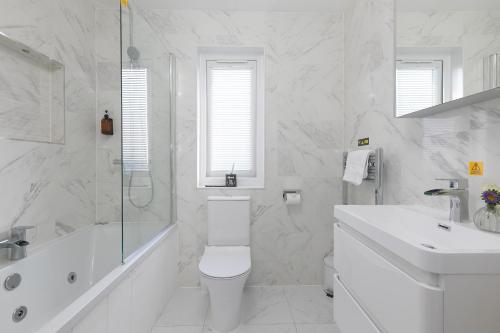 a white bathroom with a toilet and a sink at Magnolia in Portreath