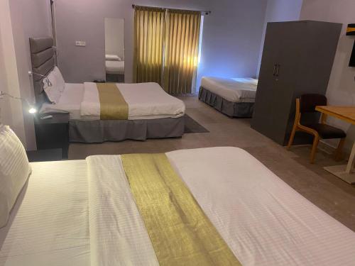 a room with two beds and a table and a desk at Shri Sai Palace inn in Chikmagalūr