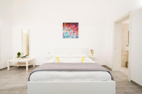 a white bedroom with a bed and a painting on the wall at Mati's in Monopoli