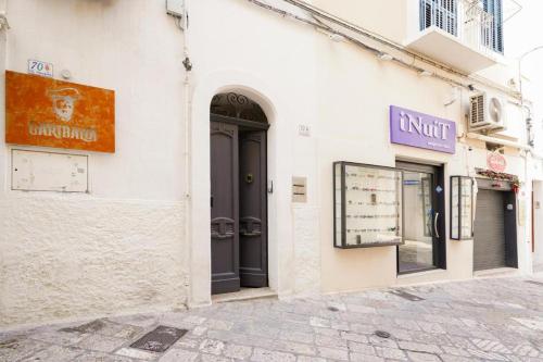 a white building with black doors on a street at Mati's in Monopoli