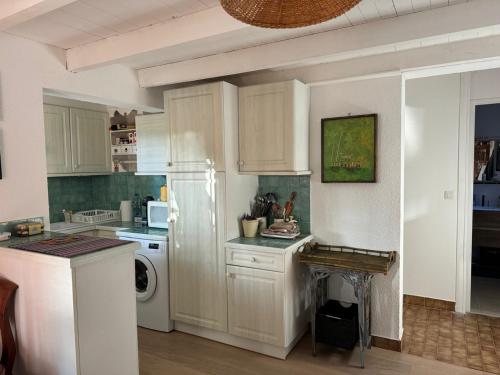  La cuisine est équipée de placards blancs et d'un réfrigérateur. dans l'établissement St Cyprien Aygual Maison avec bel exterieur, à Saint-Cyprien