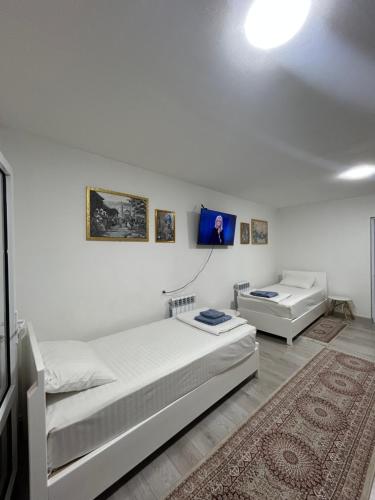 a white bedroom with two beds and a rug at Lime Apart Hotel in Bukhara