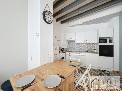 une cuisine avec une table en bois et une horloge au mur dans l'établissement La Petite Malouine - 200m plage, à Dunkerque