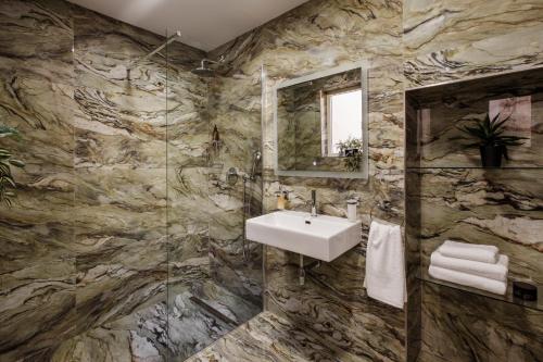 La salle de bains en pierre est pourvue d'un lavabo et d'un miroir. dans l'établissement Ellul Living, à Il-Furjana