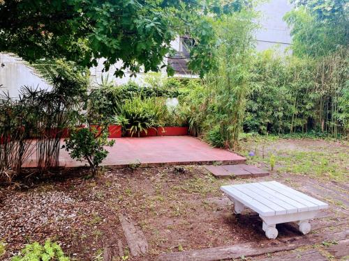 a picnic table in a garden with a bench at Calido hogar in Pinamar