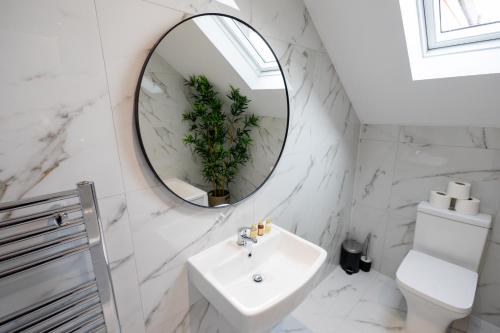 a white bathroom with a sink and a mirror at Watford Quality 3-bedroom Flat in Watford