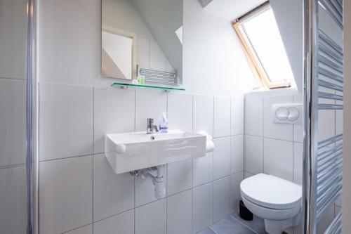 a white bathroom with a sink and a toilet at Hotel-Restaurant Loodsmans Welvaren in Den Hoorn