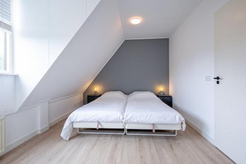 a white bedroom with a bed in a attic at Hotel-Restaurant Loodsmans Welvaren in Den Hoorn