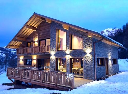 a log house with a deck in the snow at La Superba in Allos