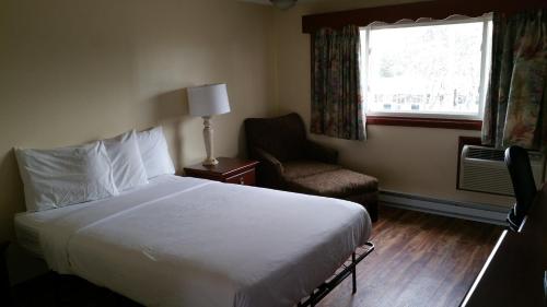a bedroom with a bed and a chair and a window at Dartmouth Motor Inn in North Dartmouth