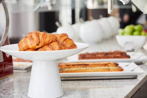 a white plate with croissants and other foods on a counter at AC Hotel by Marriott Bloomington Mall of America in Bloomington