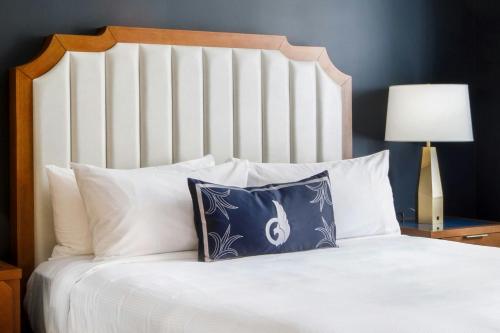 a white bed with a blue pillow on it at The National, Autograph Collection in Oklahoma City