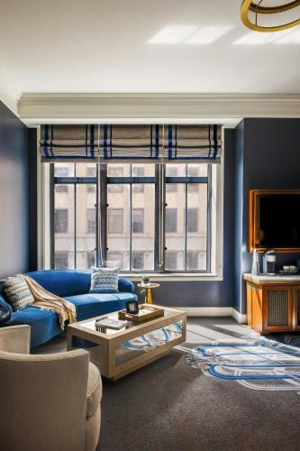 a living room with a blue couch and a tv at The National, Autograph Collection in Oklahoma City