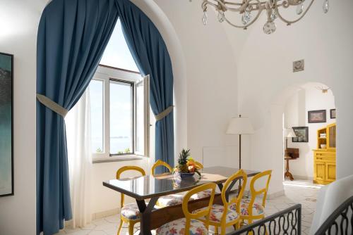 a dining room with blue curtains and a table and chairs at Hotel Eden Roc in Positano