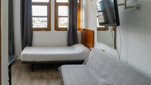 a small room with two beds and a tv at SunDos Feria Valencia in Valencia
