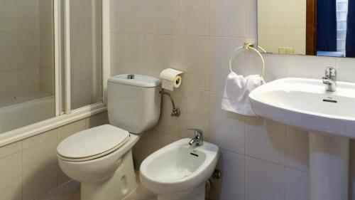 a white bathroom with a toilet and a sink at SunDos Feria Valencia in Valencia