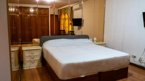 a bedroom with a large white bed and a dresser at SunDos Feria Valencia in Valencia