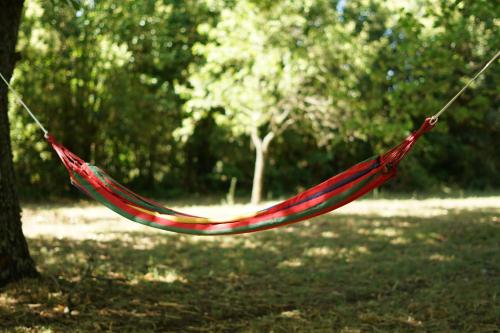 a red hammock hanging from a tree in a park at Villa Le Fate - idromassaggio in Sambuco