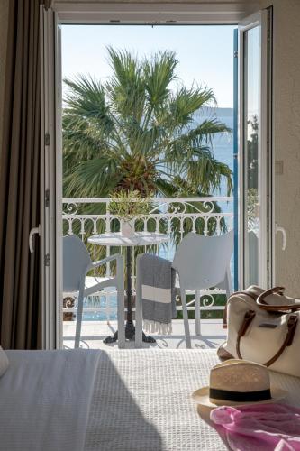 a room with a balcony with a table and chairs at Aneroussa Beach Hotel in Batsi