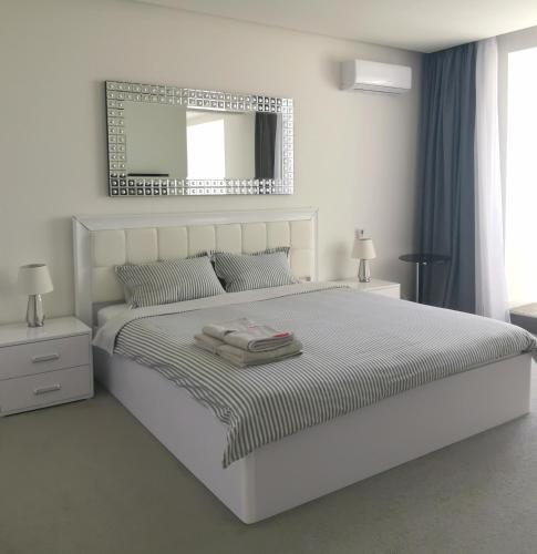 a white bedroom with a large bed with a mirror at Stylish Riverside Apartments in Riviera Complex in Mykolaiv