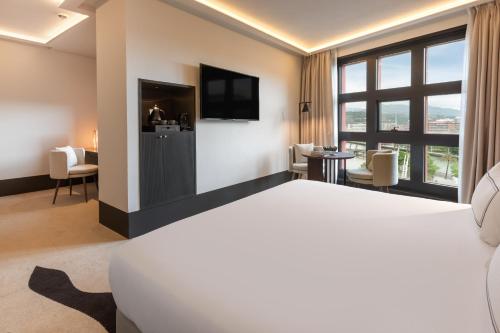 a hotel room with a bed and a flat screen tv at Hotel Meliá Bilbao in Bilbao