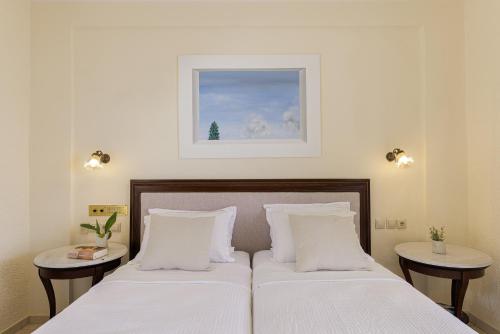 a bedroom with two beds and a picture on the wall at Aneroussa Beach Hotel in Batsi