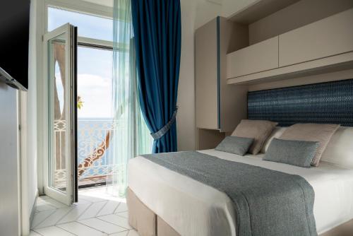 a bedroom with a large bed and a large window at Hotel Eden Roc in Positano