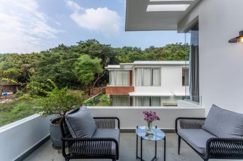a balcony with two chairs and a table at La Masillia, 2 BHK with Private Pool, 15 mins from Morjim Beach, Wifi, Peaceful location, Kitchen, Security, Patio in Siolim