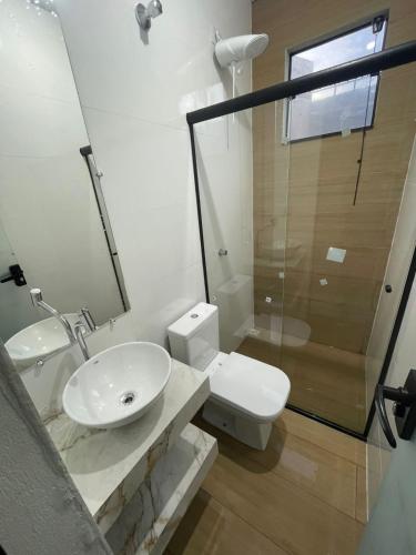 a bathroom with a sink and a toilet and a shower at Caverna Suítes - Suítes na praça matriz in São Thomé das Letras