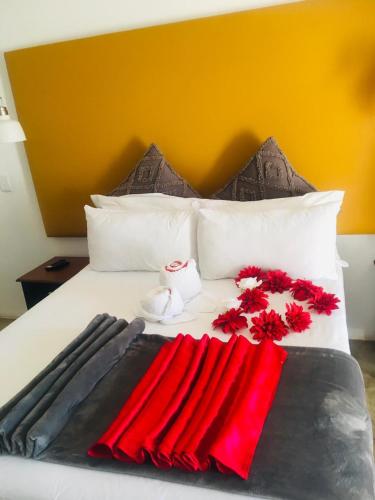 a bed with red flowers and towels on it at Ramkiki Country Restaurant and Conference Centre in Roodepoort