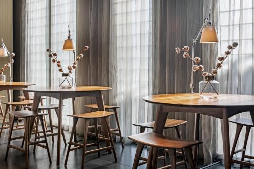 a group of tables and stools in a room with windows at AC Hotel Sants by Marriott in Barcelona
