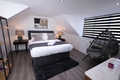a bedroom with a large bed and a chair at Modern 4-Bed Watford Flat - 20-min to London in Watford