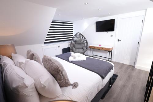 a bedroom with a bed and a chair and a desk at Modern 4-Bed Watford Flat - 20-min to London in Watford