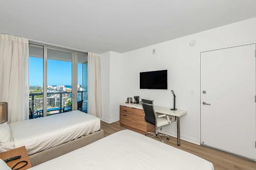 1 dormitorio con 2 camas y escritorio con ordenador en Lovely Studio with Amazing Views, en Hallandale Beach