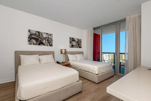 two beds in a white room with a window at Lovely Studio with Amazing Views in Hallandale Beach