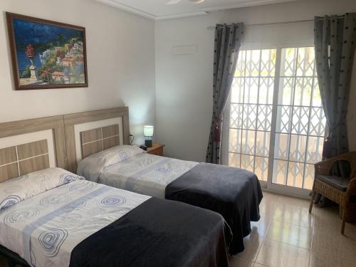 Una habitación de hotel con dos camas y una ventana. en Los Flamencos Villa, en Los Alcázares