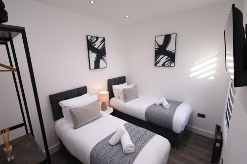 a room with two beds and a chair in it at Modern 4-Bed Watford Flat - 20-min to London in Watford