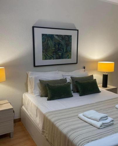 a bedroom with a large white bed with green pillows at Mar Sereno Praia Formosa in Funchal