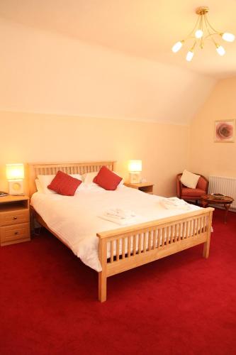 a bedroom with a large bed with white sheets and red carpet at The Red Lion in Revesby