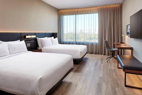 a hotel room with two beds and a desk at AC Hotel by Marriott San Jose Santa Clara in Santa Clara