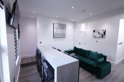 a living room with a green couch and a table at Modern 4-Bed Watford Flat - 20-min to London in Watford