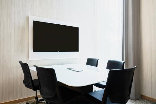 a white table with chairs and a television on a wall at AC Hotel by Marriott Miami Aventura in Aventura