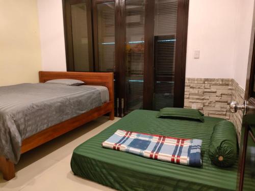 a bedroom with two beds and a green ottoman at Villa Nhà Như in Phu Quoc